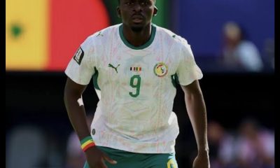 Soccer player wearing white jersey with green accents and number 9, on the field for Senegal.