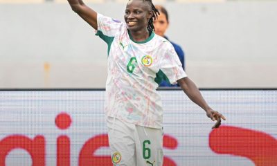 Senegal women’s footballer in a white and green kit with number 6 celebrating, arm raised on the pitch