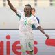 Senegal women’s footballer in a white and green kit with number 6 celebrating, arm raised on the pitch