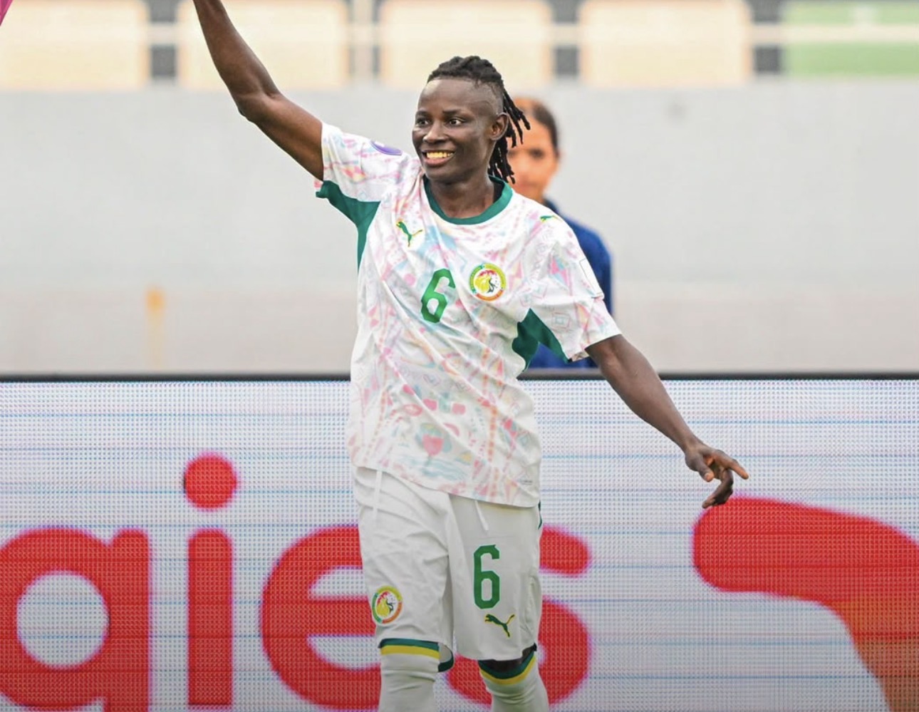 Senegal women’s footballer in a white and green kit with number 6 celebrating, arm raised on the pitch